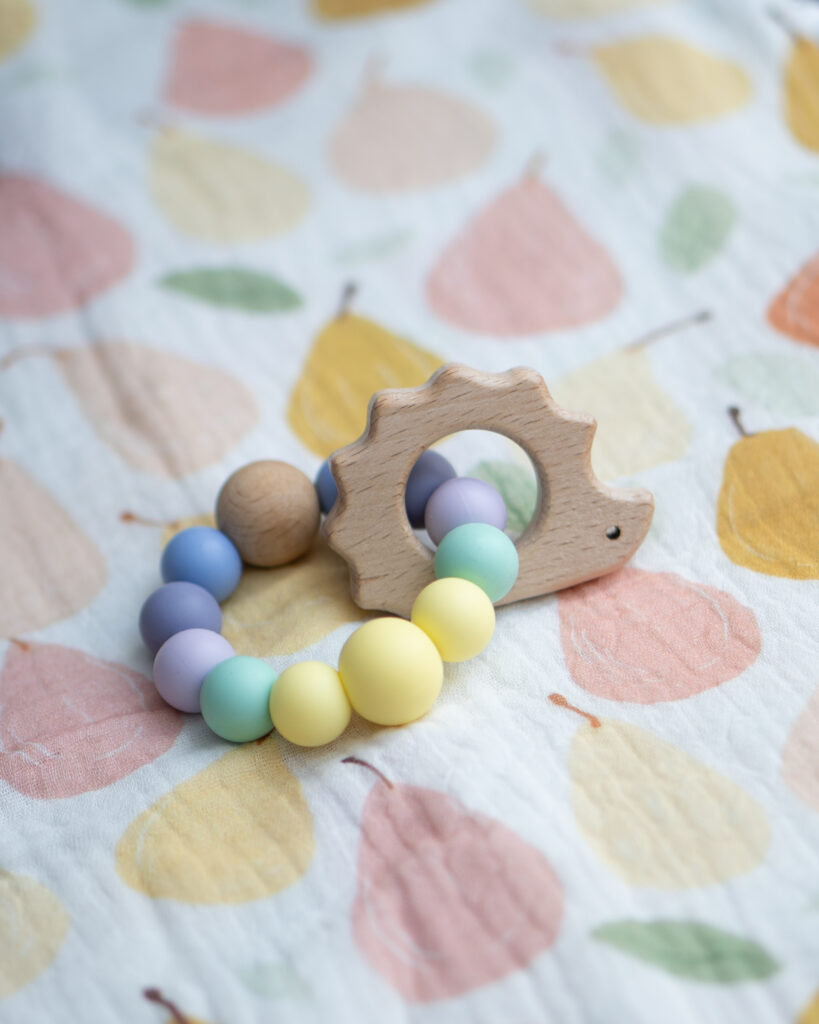Mordedor sensorial Lulumoon con figura de erizo de madera y pulsera de bolas de silicona pastel.