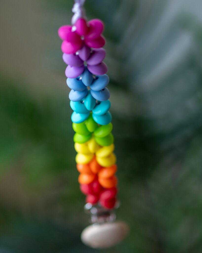 Chupetero de silicona con diseño de estrellas en colores del arcoíris y clip de madera de Lulumoon.
