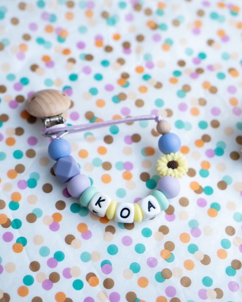 Chupetero personalizado con nombre para bebé modelo Koa en tonos lila, menta y amarillo.