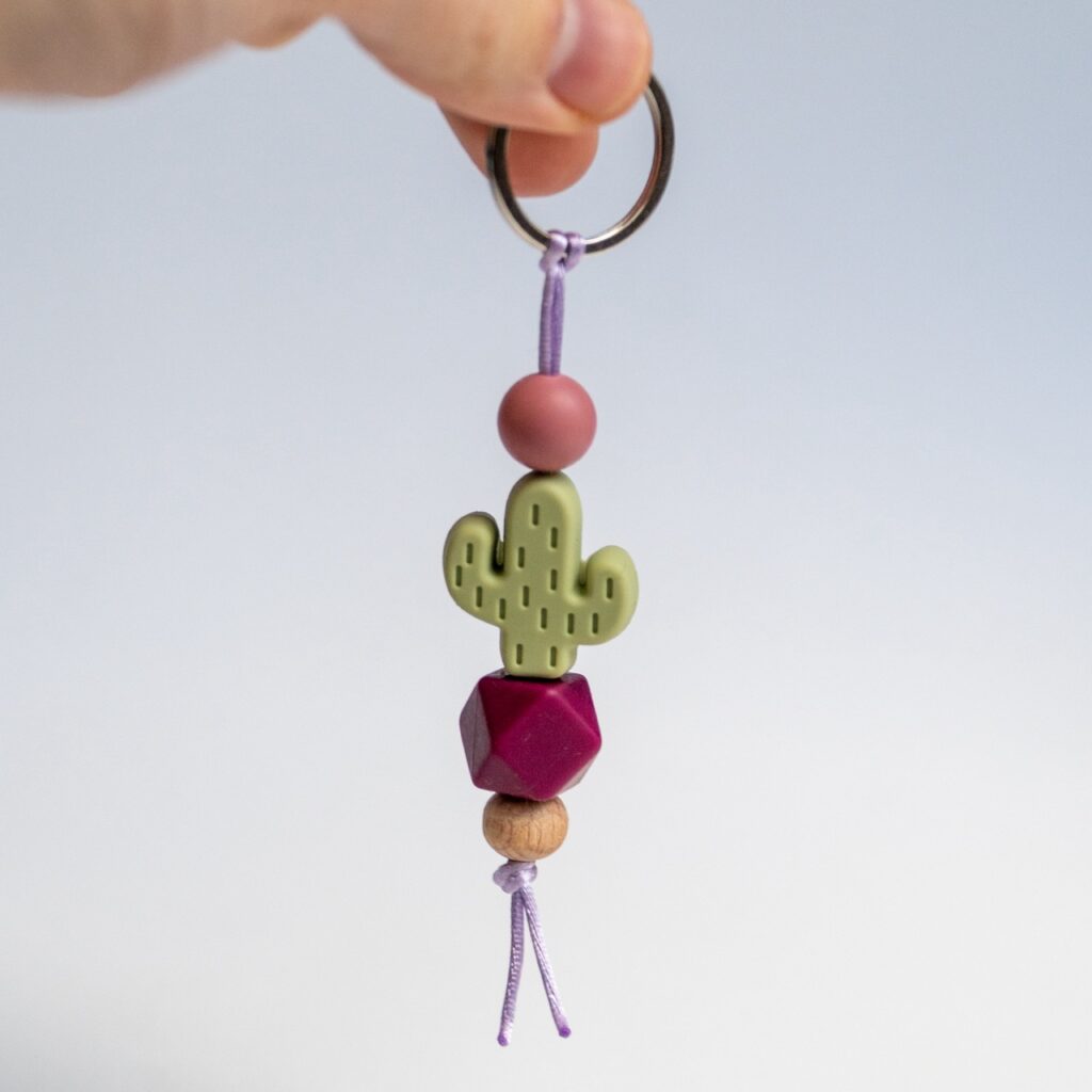 Llavero Lulumoon modelo Cactus con silicona verde, bola hexagonal morada y detalles en lila.