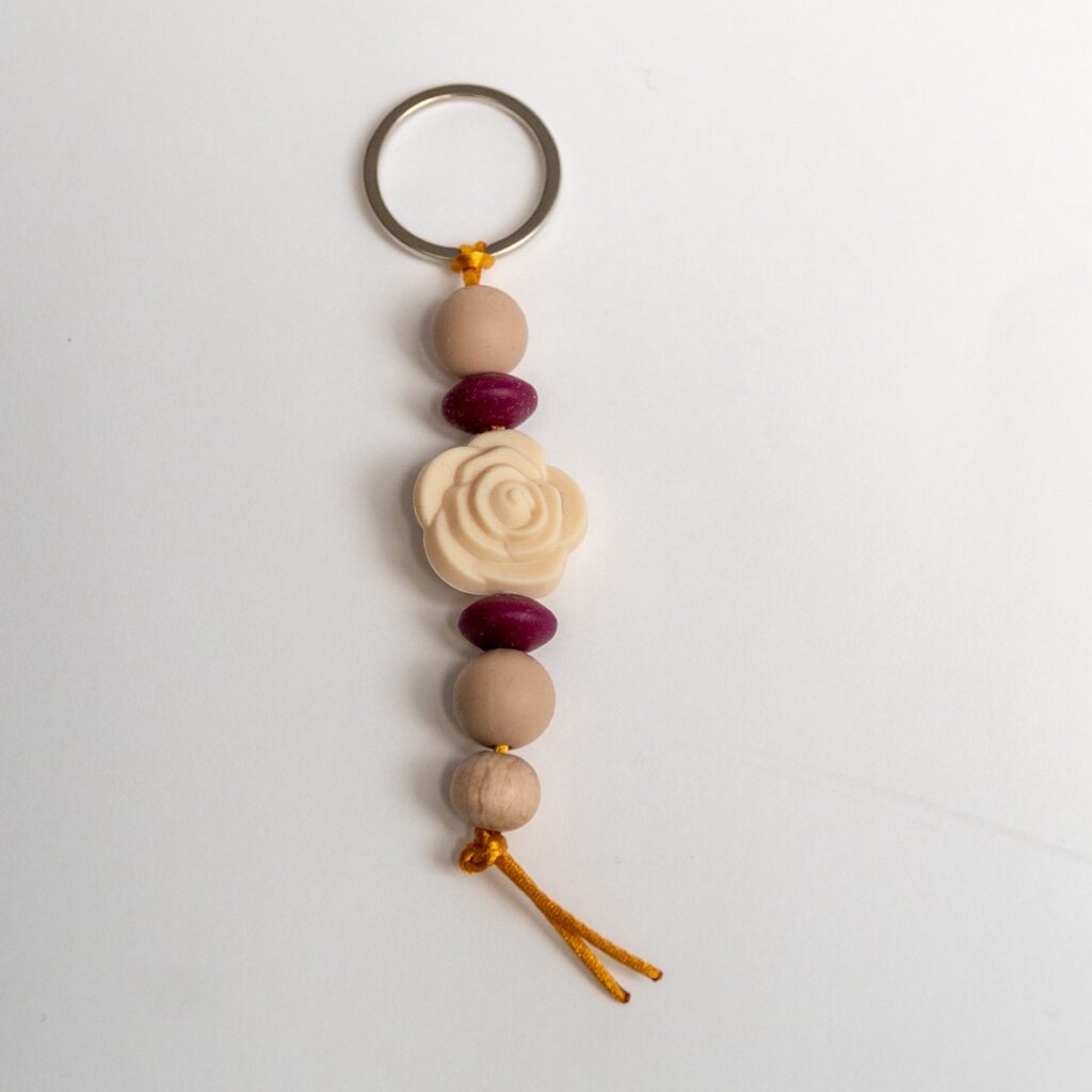 Llavero Lulumoon modelo Rosa con silicona en tonos maquillaje, detalles granate y madera de haya.