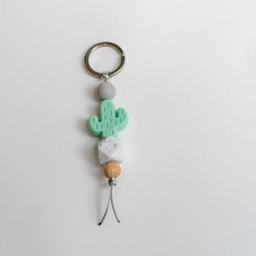 Llavero Lulumoon modelo Cactus Menta con bola hexagonal moteada y detalles en gris y madera.