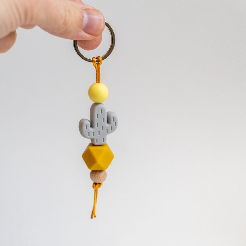 Llavero Lulumoon modelo Cactus Mostaza con silicona gris, bola amarilla y cordón mostaza.