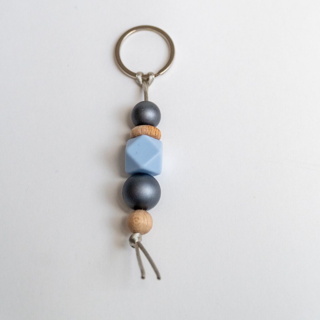 Llavero Lulumoon modelo Ártico con bolas de silicona gris metalizado, azul y madera de haya.