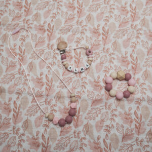 Pack de regalo para bebé Lulumoon: conjunto de chupetero personalizado con el nombre ALMA, collar de lactancia para mamá y mordedor de mano a juego, en tonos rosa terracota, polvo y beige con madera natural, sobre tela estampada con hojas.